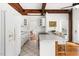 Bright kitchen with wooden beams, white cabinetry, and stainless steel appliances at 406 Johns Woods Rd, Chapel Hill, NC 27516