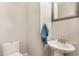 Small half bathroom featuring a white toilet, pedestal sink, a gray framed mirror, and a blue hand towel at 411 E Green St, Franklinton, NC 27525