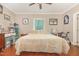 Light-filled bedroom with hardwood floors, a ceiling fan, and a bed with colorful throw pillows and textured linens at 411 E Green St, Franklinton, NC 27525