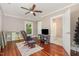 Bright bedroom featuring hardwood floors, a ceiling fan, rocking chair, and access to an adjacent bathroom at 411 E Green St, Franklinton, NC 27525