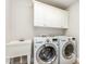 Functional laundry room featuring a utility sink and modern, front-loading washer and dryer at 50 Pebble Creek Dr, Franklinton, NC 27525