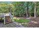 A backyard featuring a wooded lot with a wooden deck and steps leading down to a stone pathway at 5121 Ten Point Trl, Wake Forest, NC 27587