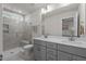 Bright bathroom featuring a double vanity with gray cabinets and a tiled shower with a window at 518 Toran Dr, Wake Forest, NC 27587