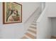 Elegant staircase with white wainscoting, wooden steps and a striking framed vintage poster at 518 Toran Dr, Wake Forest, NC 27587