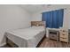 Cozy bedroom with wood-look floors, window with blue curtains, and wood bedside table with drawers at 5301 Northpines Dr, Raleigh, NC 27610