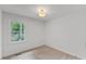 A bright bedroom features neutral carpet, natural light, and modern lighting fixture at 702 Sanderson Dr, Durham, NC 27704
