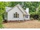 View of the home's front facade showing the white siding, brick foundation, and professionally landscaped front yard at 702 Sanderson Dr, Durham, NC 27704