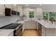 Spacious kitchen has white cabinetry, stainless appliances, stone counters, and access to deck at 702 Sanderson Dr, Durham, NC 27704