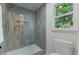 Walk-in shower with green tile, recessed niche, glass enclosure, and adjacent toilet at 702 Sanderson Dr, Durham, NC 27704