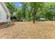 Spacious, landscaped side yard featuring mature trees, pine straw ground cover, and classic white picket fence at 702 Sanderson Dr, Durham, NC 27704