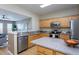Well-lit kitchen with stainless steel appliances, wood cabinets, and adjacent living area at 7244 Galon Glen Rd, Raleigh, NC 27613
