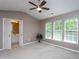 The primary bedroom features an ensuite bathroom, three windows allowing ample natural light, and neutral carpeting at 7244 Galon Glen Rd, Raleigh, NC 27613