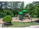 Community playground with slides, climbing structure, and green canopy, surrounded by trees and black metal fence at 7244 Galon Glen Rd, Raleigh, NC 27613