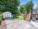 Back patio with stone pavers, wooden steps, and a fenced-in lawn with a storage shed offers a relaxing backyard space at 8312 Bellingham Cir, Raleigh, NC 27615