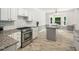 Bright kitchen featuring granite counters, white cabinets, a tile backsplash, and stainless steel appliances at 8312 Bellingham Cir, Raleigh, NC 27615