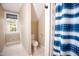 Well-lit bathroom with window, toilet, and a blue patterned shower curtain for privacy and style at 9200 Lake Carol Dr, Zebulon, NC 27597