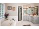 Well-lit bathroom featuring a soaking tub with jets, glass block window, vanity with sink and black hardware at 9200 Lake Carol Dr, Zebulon, NC 27597