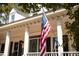 Close-up of the front porch with decorative columns and a view of the front door and an American flag at 9200 Lake Carol Dr, Zebulon, NC 27597