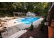 Backyard view of a well-maintained pool with an expansive patio and mature landscaping at 9200 Lake Carol Dr, Zebulon, NC 27597