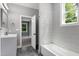 Bright bathroom features gray tile floors, a tiled shower, and a view into an adjacent bedroom at 1003 E Sterlington Pl, Apex, NC 27502
