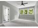 Bright bedroom with neutral carpet, ceiling fan, and large windows overlooking greenery at 1003 E Sterlington Pl, Apex, NC 27502