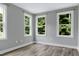 Bedroom with light gray walls, hardwood floors, three large windows with views of the backyard at 1003 E Sterlington Pl, Apex, NC 27502