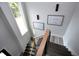 Stylish staircase featuring dark wood steps, a light wood handrail, and modern metal balusters under a large window at 1003 E Sterlington Pl, Apex, NC 27502