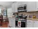 Close-up of the stainless steel oven and granite countertop and backsplash in this eat-in kitchen with white cabinetry at 1012 Autumn Meadow Ln, Wake Forest, NC 27587