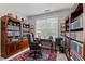 Comfortable home office with dark wood bookshelves, a window with blinds, a plush chair, and a red patterned rug at 1012 Autumn Meadow Ln, Wake Forest, NC 27587