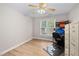 Cozy bedroom with wood flooring, a large window, and an adjacent desk area with filing cabinets at 111 Gingergate Dr, Cary, NC 27519