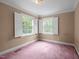 This bedroom boasts natural light from two large windows with white shutters and pink carpet at 12088 Burlington Rd, Hurdle Mills, NC 27541
