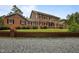 Two-story brick home with a lush lawn, framed by a brick fence and gravel driveway at 12088 Burlington Rd, Hurdle Mills, NC 27541