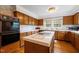 Well-lit kitchen featuring wood cabinets, white tile countertops, and an island cooktop at 12088 Burlington Rd, Hurdle Mills, NC 27541