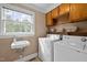 Bright laundry room features large window, sink, washer, dryer, and built-in shelving for storage at 12088 Burlington Rd, Hurdle Mills, NC 27541