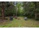 Picturesque backyard area with a fire pit and outdoor seating surrounded by trees and greenery at 12088 Burlington Rd, Hurdle Mills, NC 27541