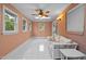 Sunroom with white tiled floors, floral sofa, and many windows at 12088 Burlington Rd, Hurdle Mills, NC 27541
