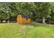 Backyard with a wooden shed, fire pit, mature trees, and green grass at 133 Creekstone Dr, Benson, NC 27504