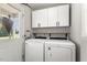 Bright laundry room features modern washer and dryer, stylish backsplash, and ample white storage cabinets at 133 Creekstone Dr, Benson, NC 27504