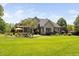 A view of the backyard featuring manicured lawn, mature trees, and patio area at 154 Sicily Dr, Clayton, NC 27527