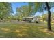 This home boasts a large backyard, covered porch, and mature trees on a sunny day at 1593 E Washington Ave, Creedmoor, NC 27522