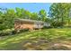 Brick home featuring a spacious, well-maintained lawn with lush greenery and mature trees at 1593 E Washington Ave, Creedmoor, NC 27522
