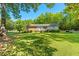 Charming single-story home with a spacious front yard and mature trees under a bright blue sky at 1593 E Washington Ave, Creedmoor, NC 27522