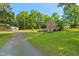 Backyard view showcasing home, brick exterior, gravel driveway, garage, and large backyard at 1593 E Washington Ave, Creedmoor, NC 27522