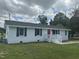 Inviting single-story home with a red front door, crisp white exterior, black shutters, and lush green lawn at 1676 Richardson Bass Rd, Kenly, NC 27542