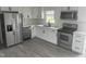 Bright kitchen featuring white cabinets, stainless steel appliances, granite countertops, and gray wood-look flooring at 1676 Richardson Bass Rd, Kenly, NC 27542