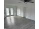 Spacious living room with wood-look flooring, decorative wall paneling, bright white paint, and double doors to a deck at 1676 Richardson Bass Rd, Kenly, NC 27542