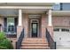 Inviting front entrance with brick stairs, iron railings, a covered porch and stylish black front door at 1716 Longmont Dr, Wake Forest, NC 27587