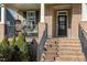 Inviting front porch with brick steps, black railing, with brick columns and a comfortable wicker swing chair at 1716 Longmont Dr, Wake Forest, NC 27587