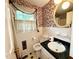 Vintage bathroom with white tile, black accents, sink, and decorative wallpaper for a unique retro style at 1818 Brookrun Rd, Henderson, NC 27536