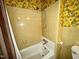 Retro bathroom showcasing tiled shower/tub with floral wallpaper at 1818 Brookrun Rd, Henderson, NC 27536